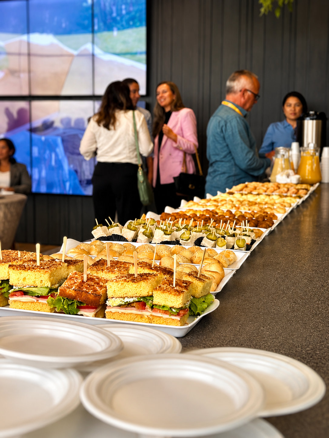 Mesa de coffee break corporativo com sanduíches, canapés e sucos servida pela Evínia